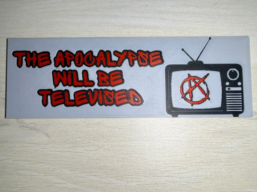 A rectangular sticker with a light gray background featuring a retro television icon with a red anarchy symbol and red text that reads 'THE APOCALYPSE WILL BE TELEVISED', displayed on a light wood surface.